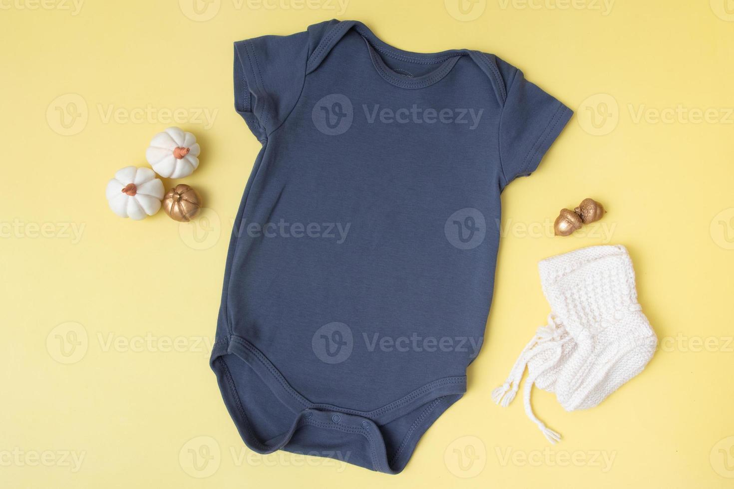 baby clobodysuit-model met pompoenen op gele achtergrond voor uw tekst of logo in het herfstseizoen foto
