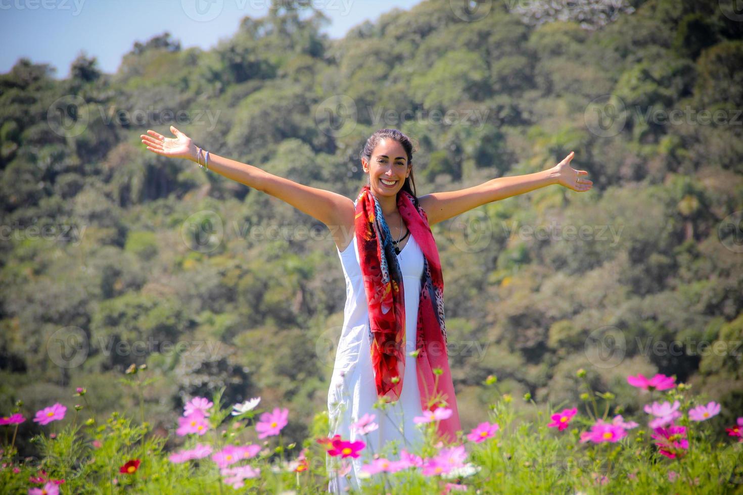 zorgeloze jonge vrouw die in een bloemenveld staat met bergen op de achtergrond foto