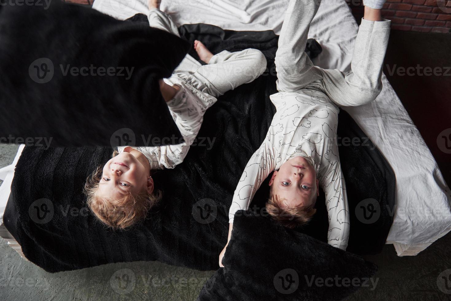 stoute kinderen kleine jongen en meisje voerden een kussengevecht op het bed in de slaapkamer. ze houden van dat soort spel foto