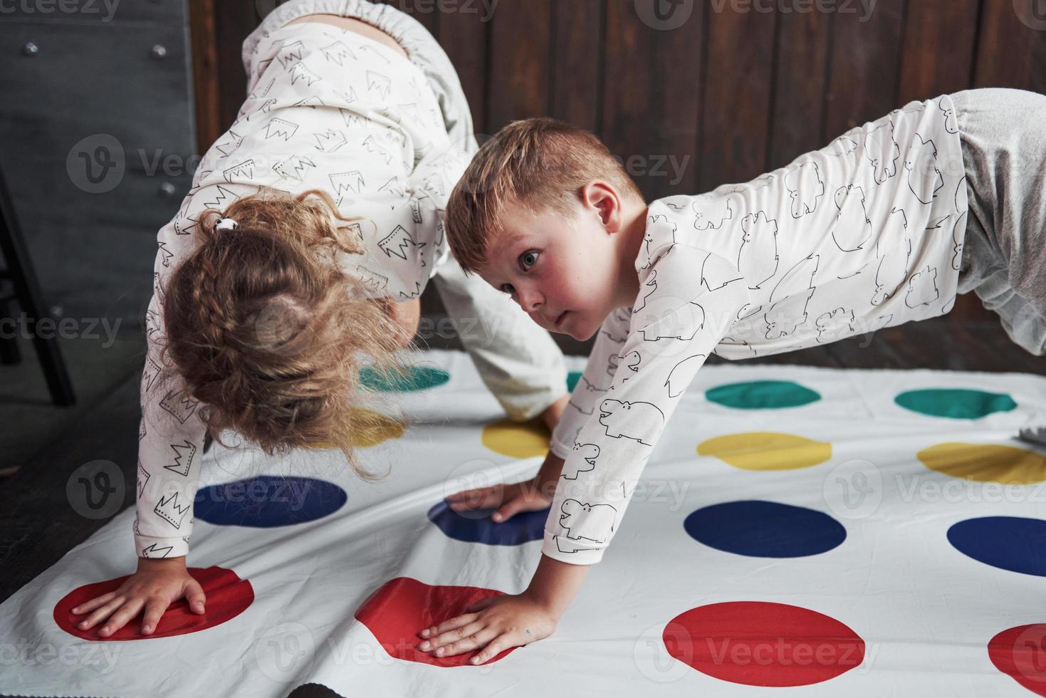 twee gelukkige kinderen die in huis bij twister spelen. broer en zus veel plezier op vakantie foto