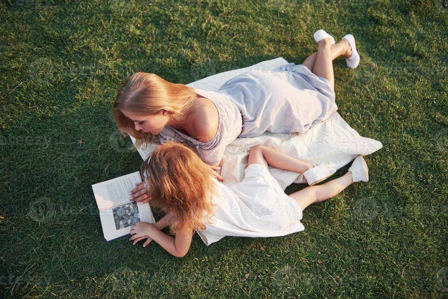 moeder met een kind leest een boek op het gras foto