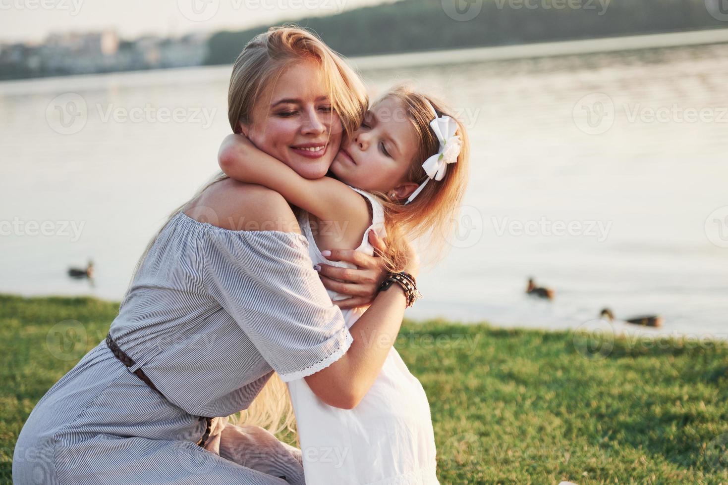 gelukkige jonge moeder met een speelse dochter in een park in de buurt van het water foto