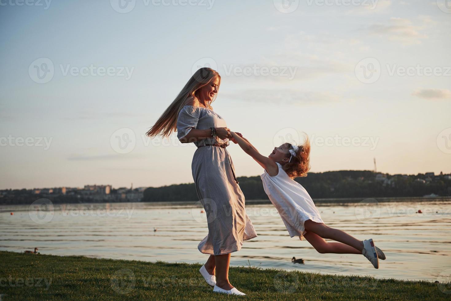 moeder en haar dochtertje spelen op het gras bij het meer. foto