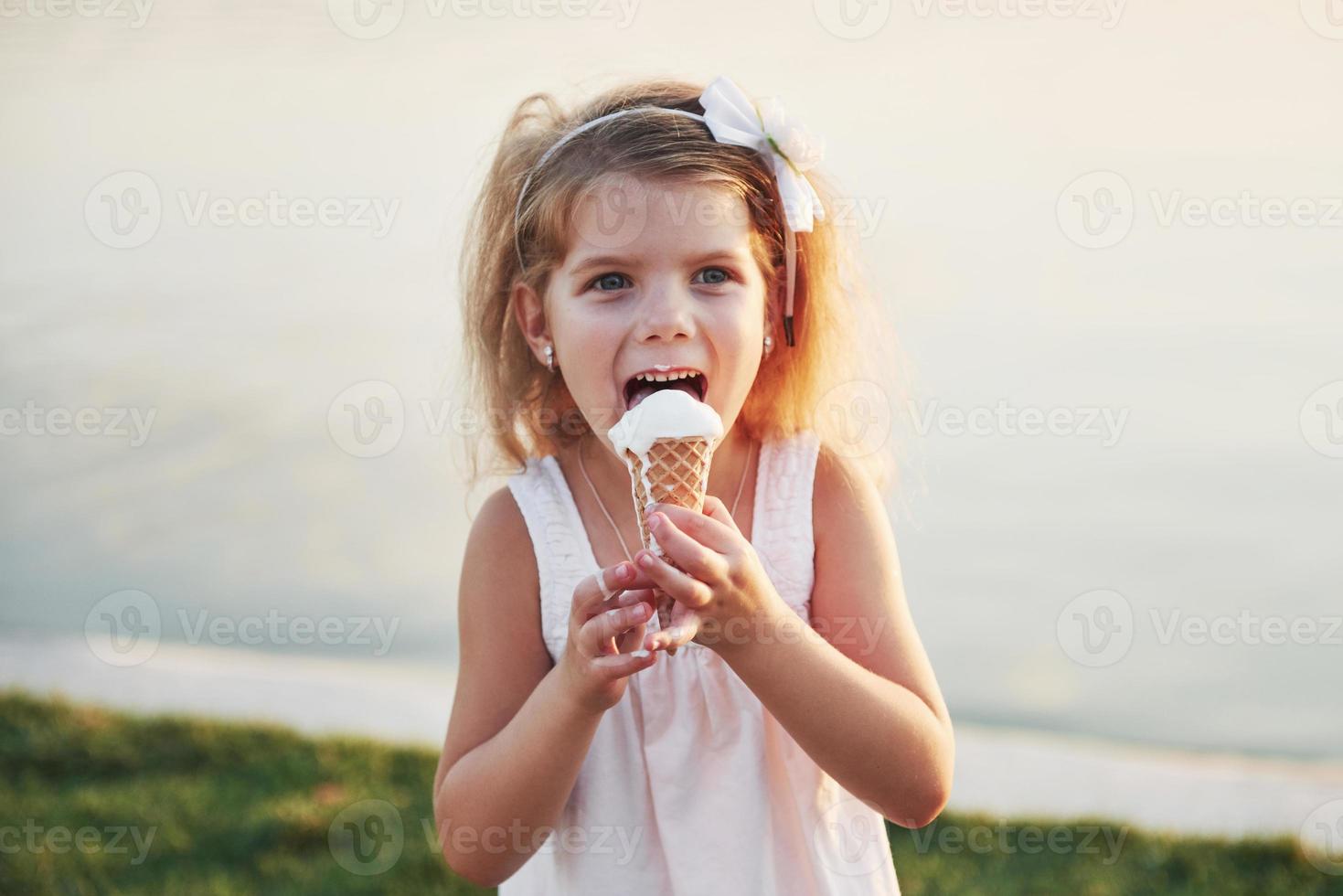 een mooi klein meisje eet een ijsje bij het water foto