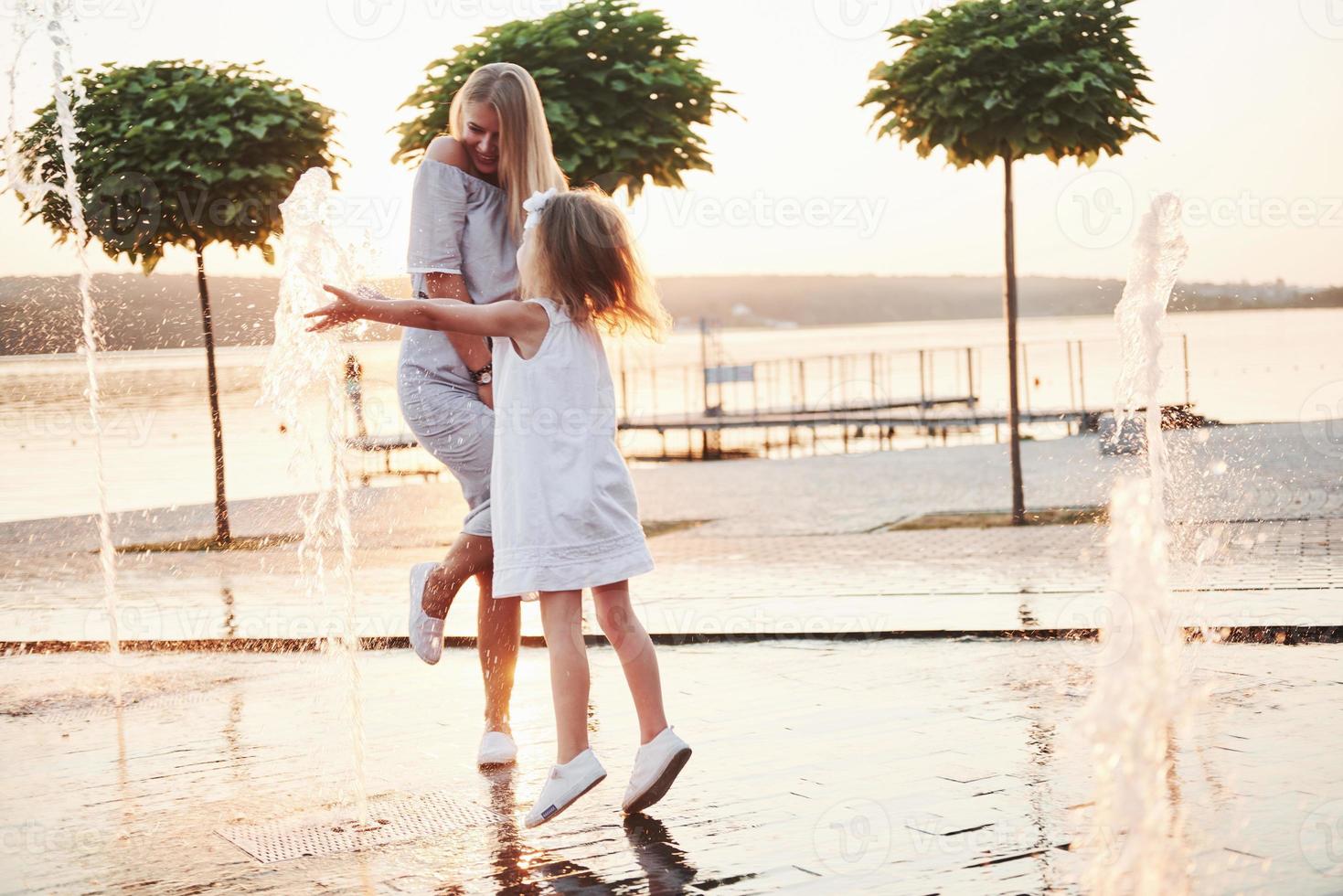 een vrouw speelt met een kind in de buurt van de oceaan in het park bij zonsondergang foto