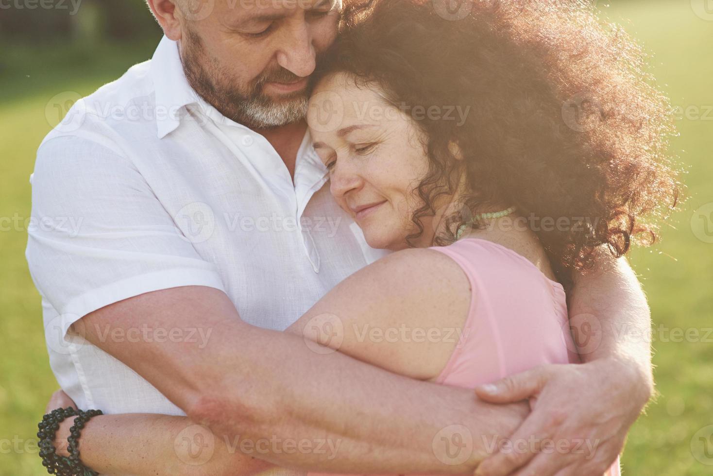 een liefdevol, knap senior koppel buiten in het park, vele jaren samen foto