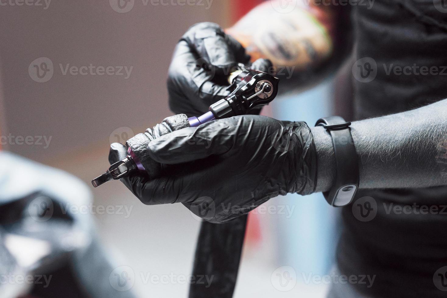 artiest met tattoo-machine in zijn studio, hij is klaar om de klant te accepteren foto