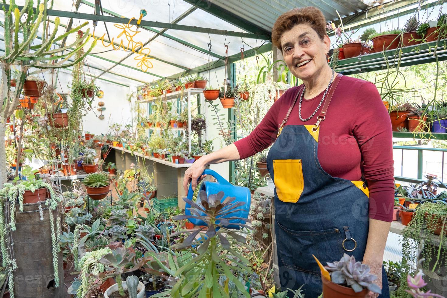 gelukkige volwassen vrouw die voor haar planten zorgt en ze water geeft, in haar tuin foto