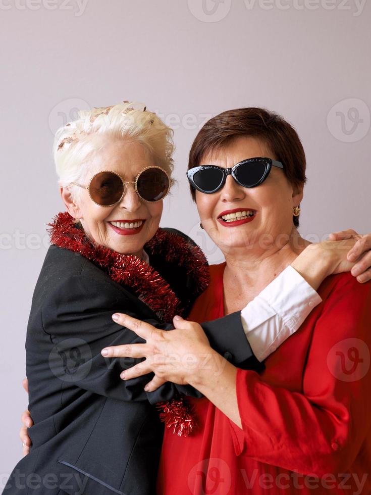 twee mooie stijlvolle volwassen senior vrouwen in zonnebril knuffelen. plezier, feest, stijl, feestconcept foto