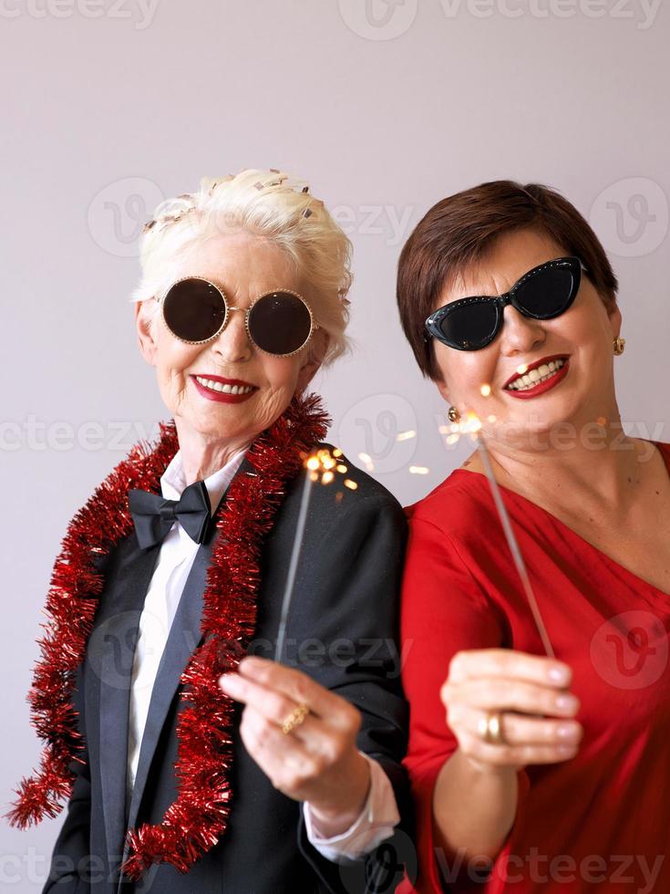 twee mooie stijlvolle volwassen senior vrouwen in zonnebril nieuwjaar vieren. plezier, feest, stijl, feestconcept foto