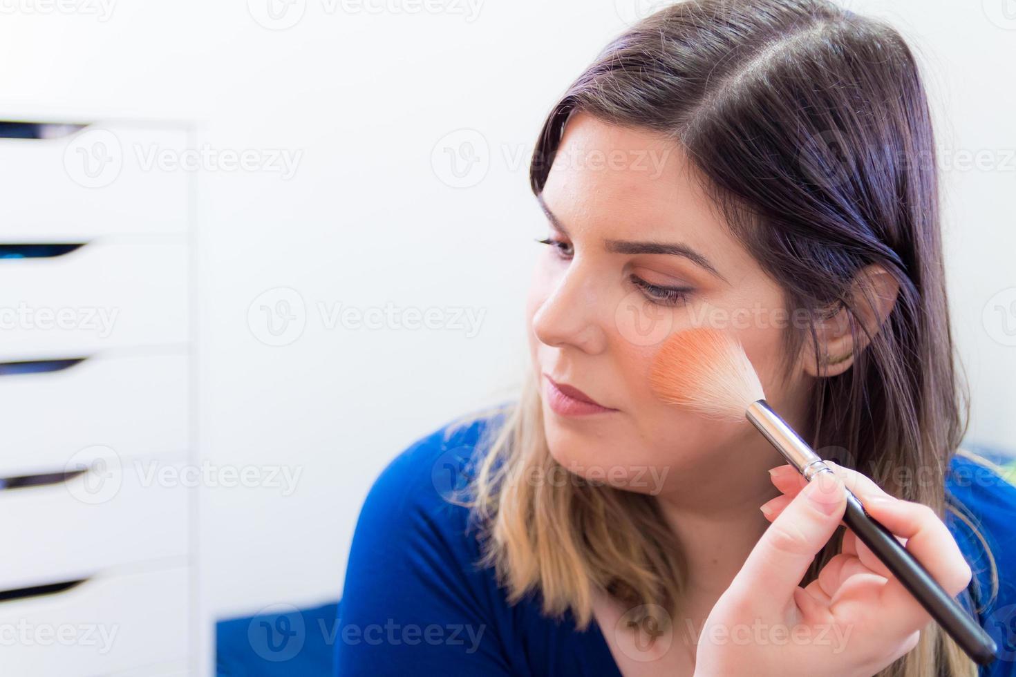 vrouw die make-up aanbrengt in haar slaapkamer foto