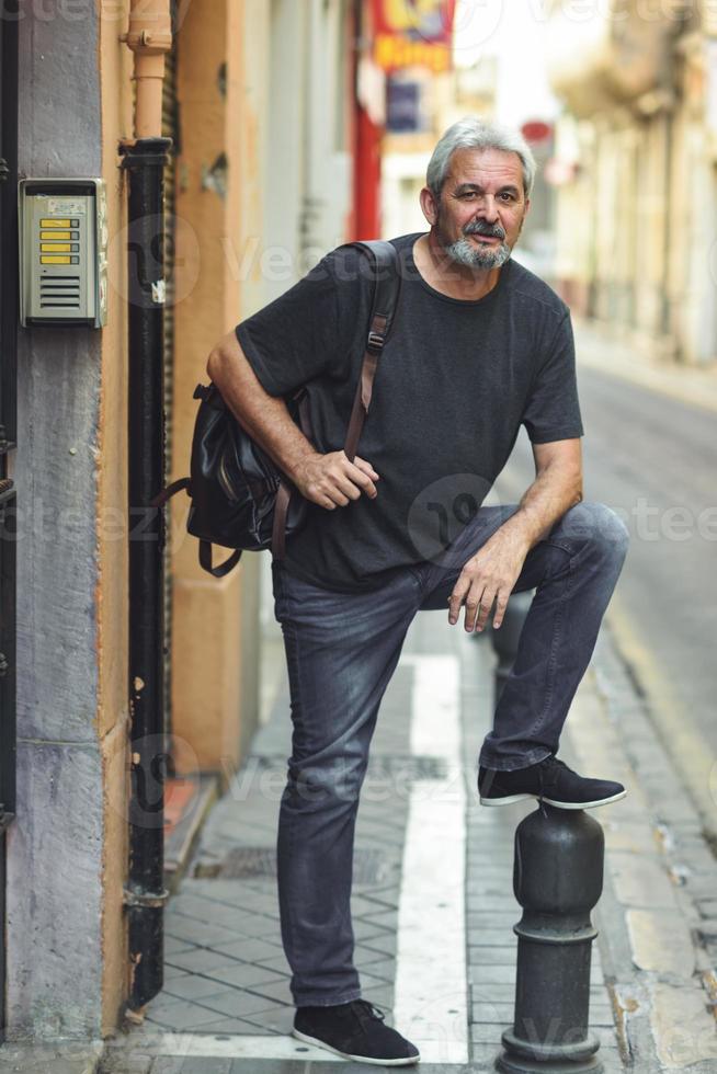 volwassen toeristische man met reisrugzak in stedelijke achtergrond. foto