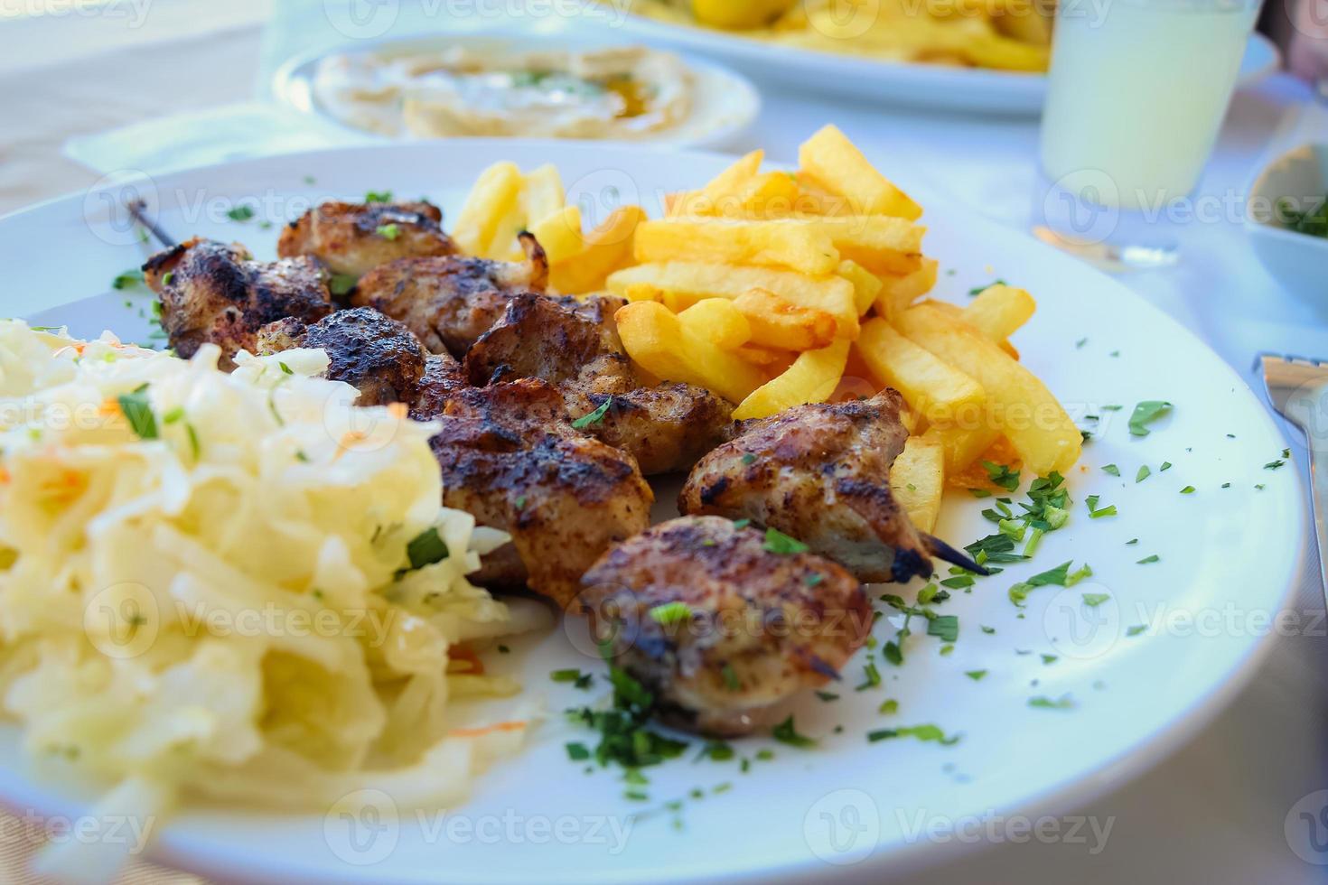 gegrilde sjasliek met frietjes op bord foto