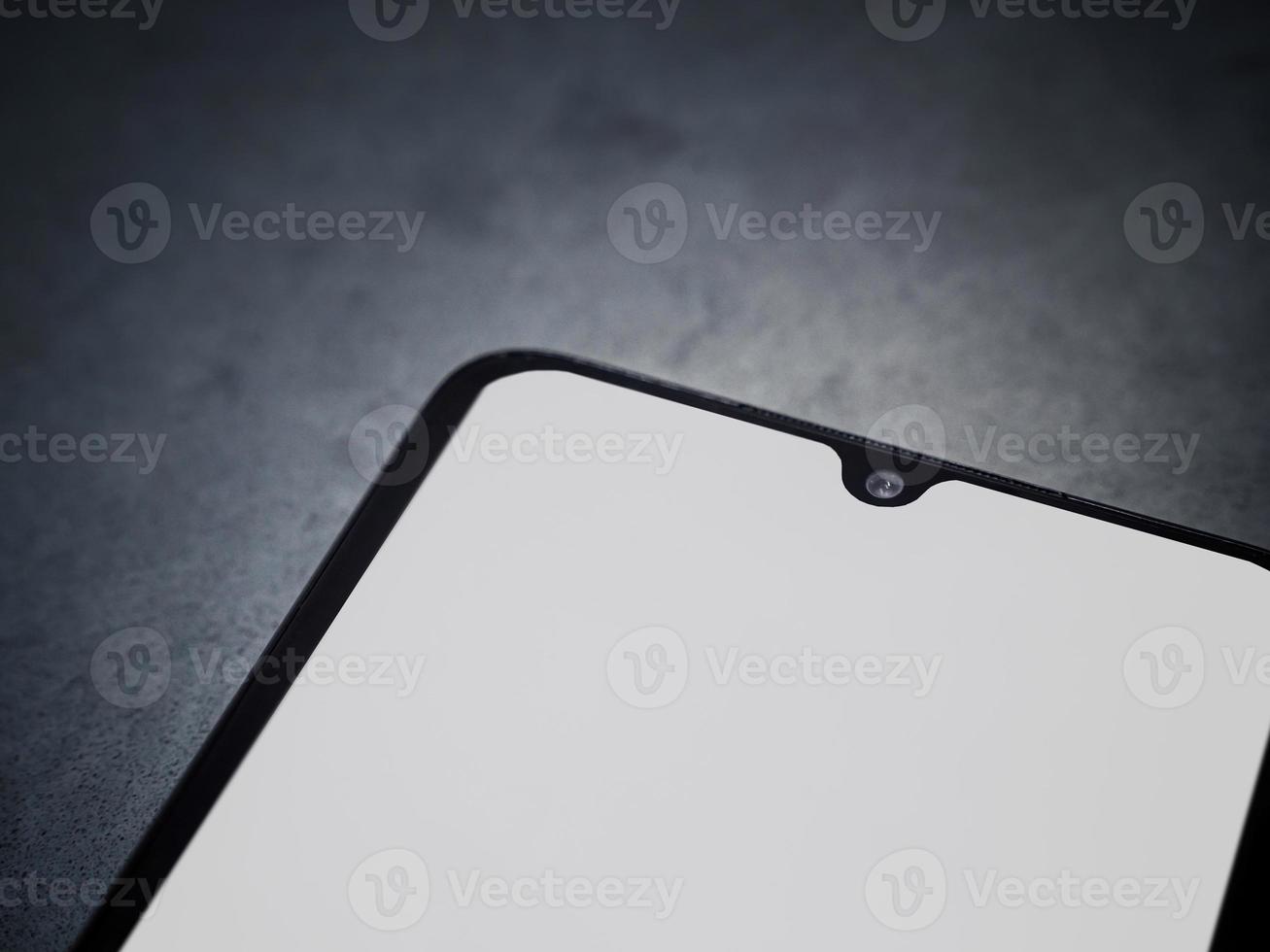 zwarte mobiele smartphone mockup ligt op het oppervlak met een leeg scherm geïsoleerd op een donkere marmeren stenen achtergrond foto