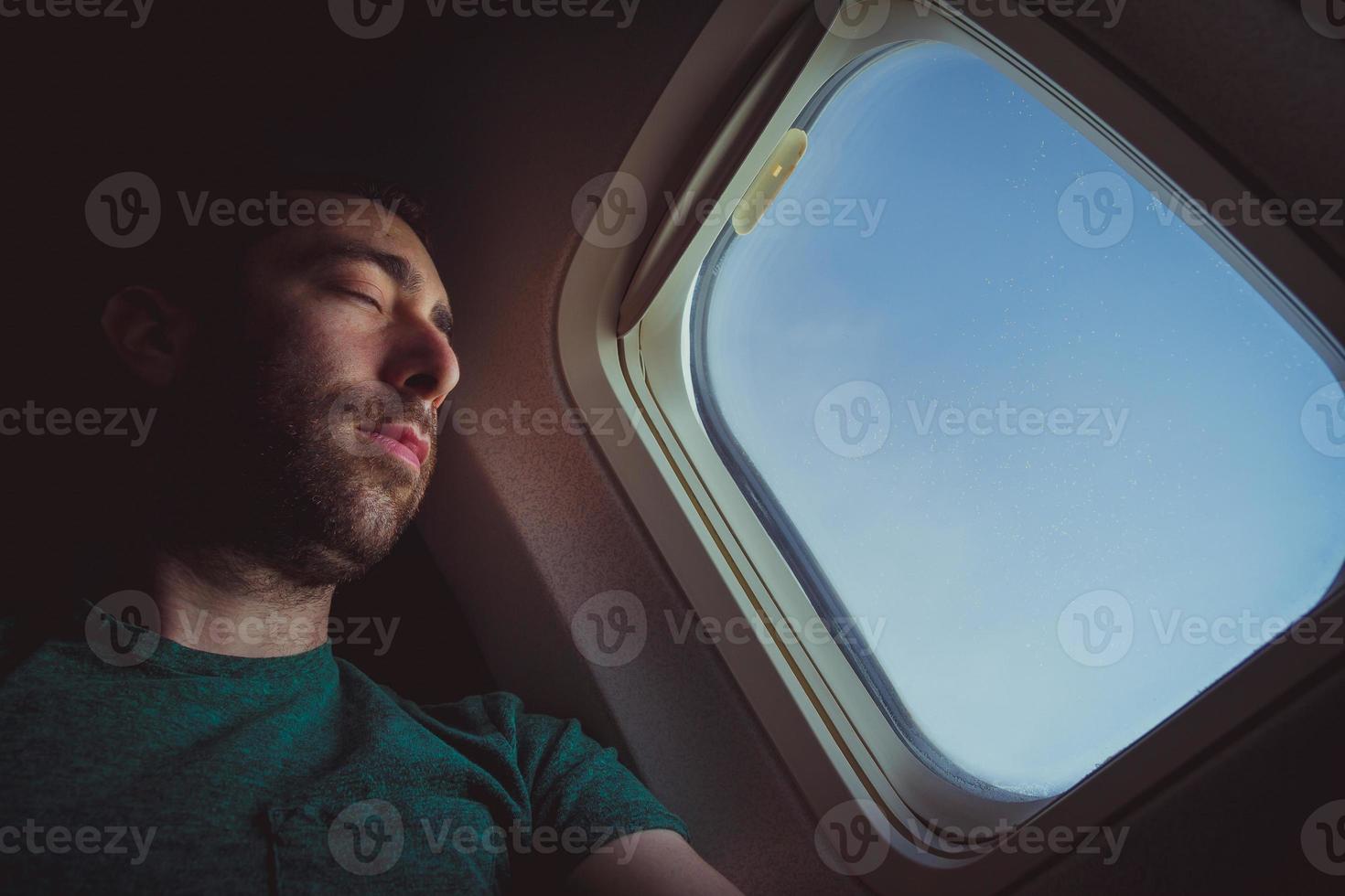jonge man rusten en slapen in een vliegtuig foto