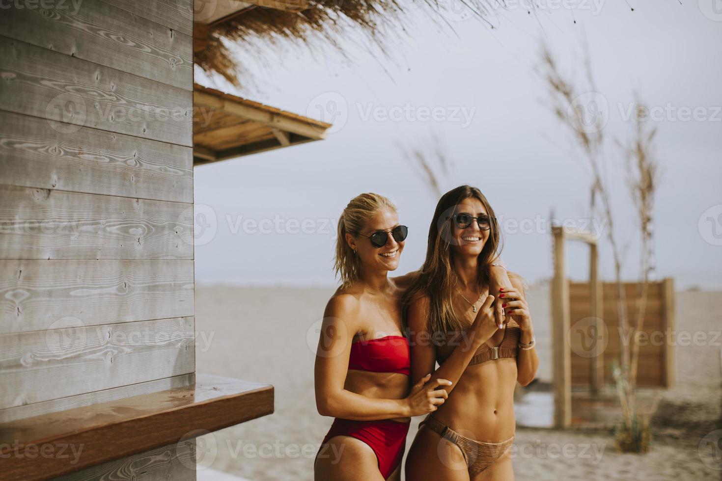 jonge vrouwen in bikini staan bij de surfcabine op een strand op een zomerdag foto