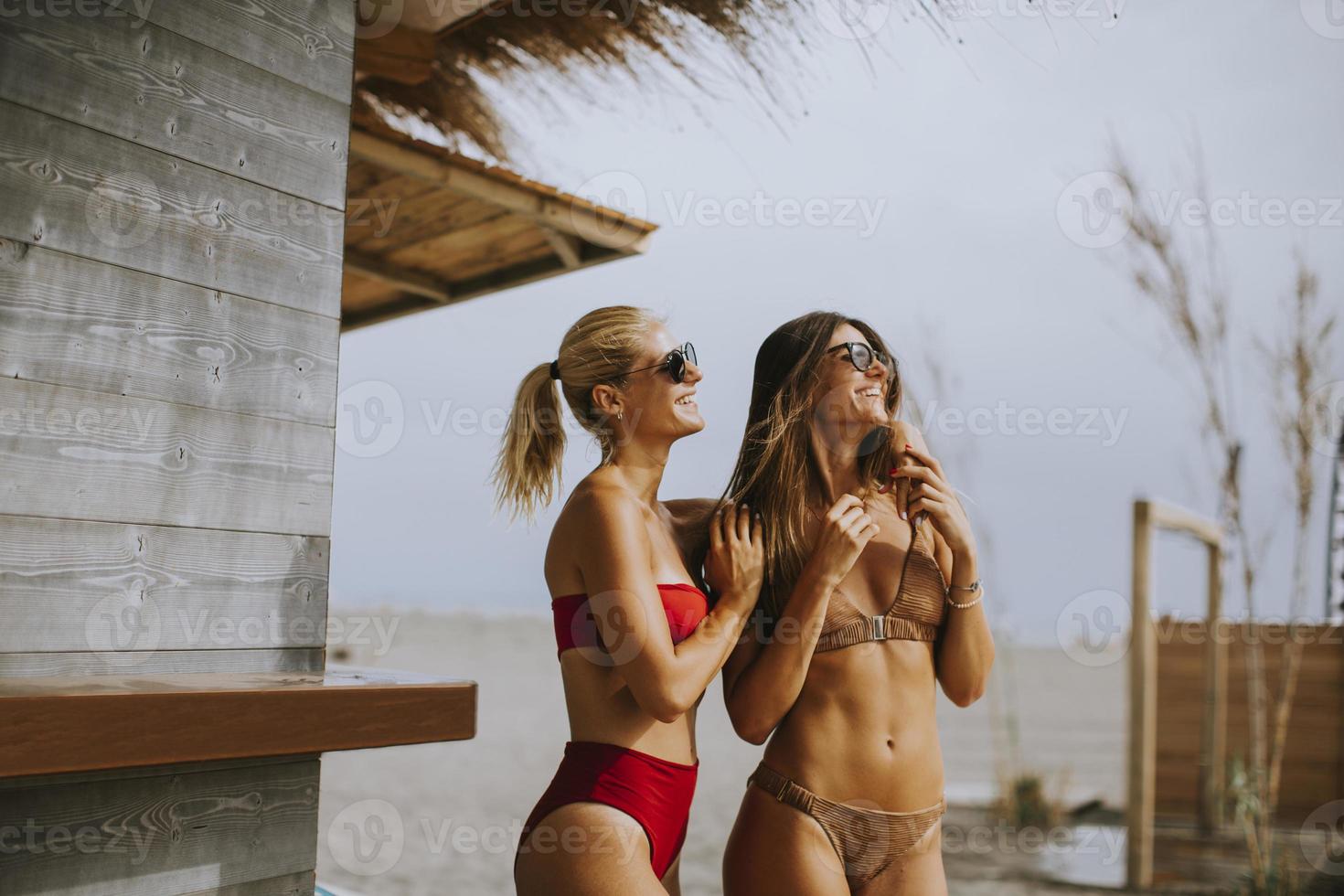 jonge vrouwen in bikini staan bij de surfcabine op een strand op een zomerdag foto