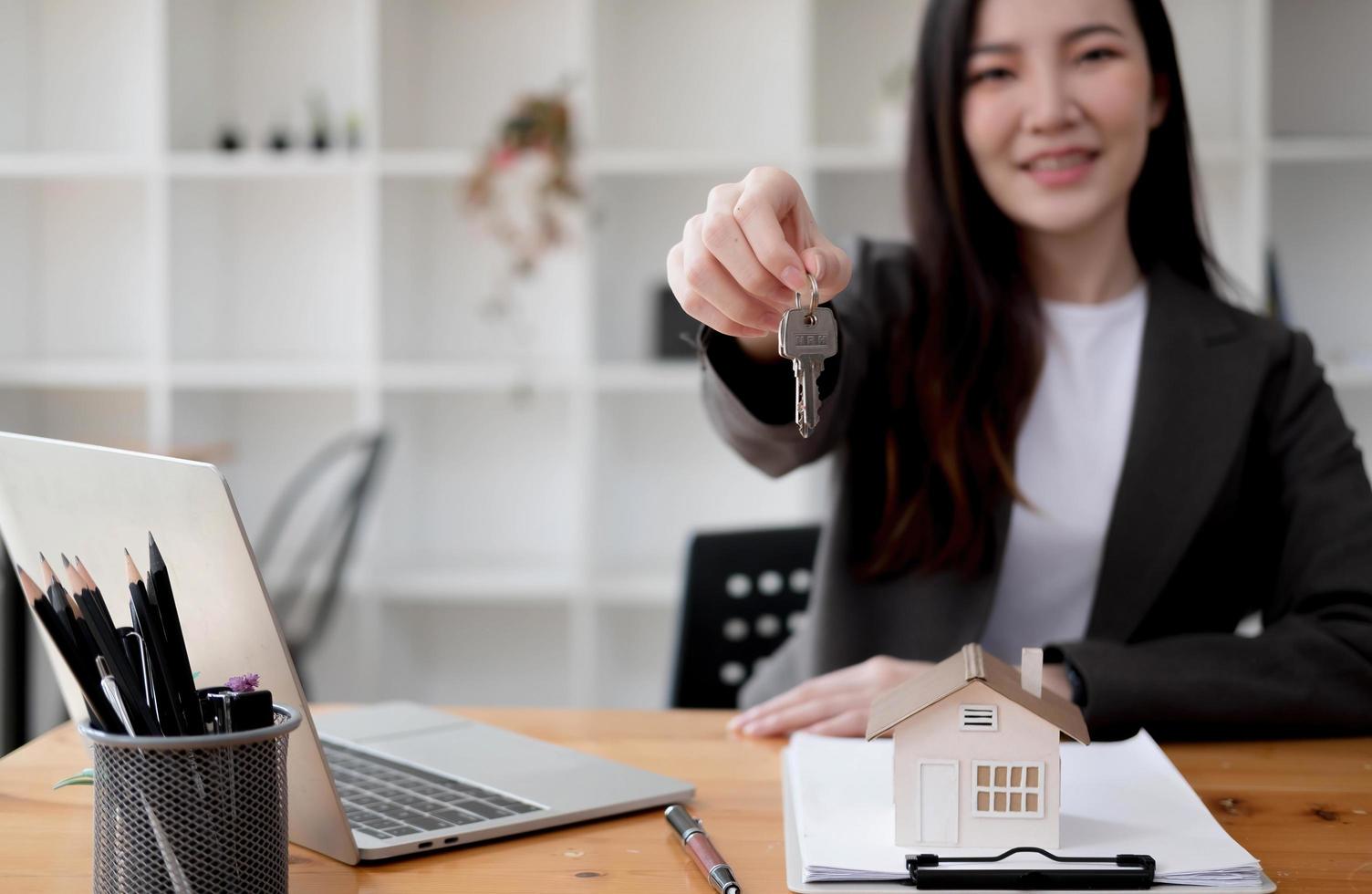 close-up focus op sleutels, glimlachende vrouw makelaar die appartement verkoopt, aanbieden aan klant, tonen op camera, documenten vasthouden, contract, koopovereenkomst sluiten, makelaar, hypotheek of huur foto