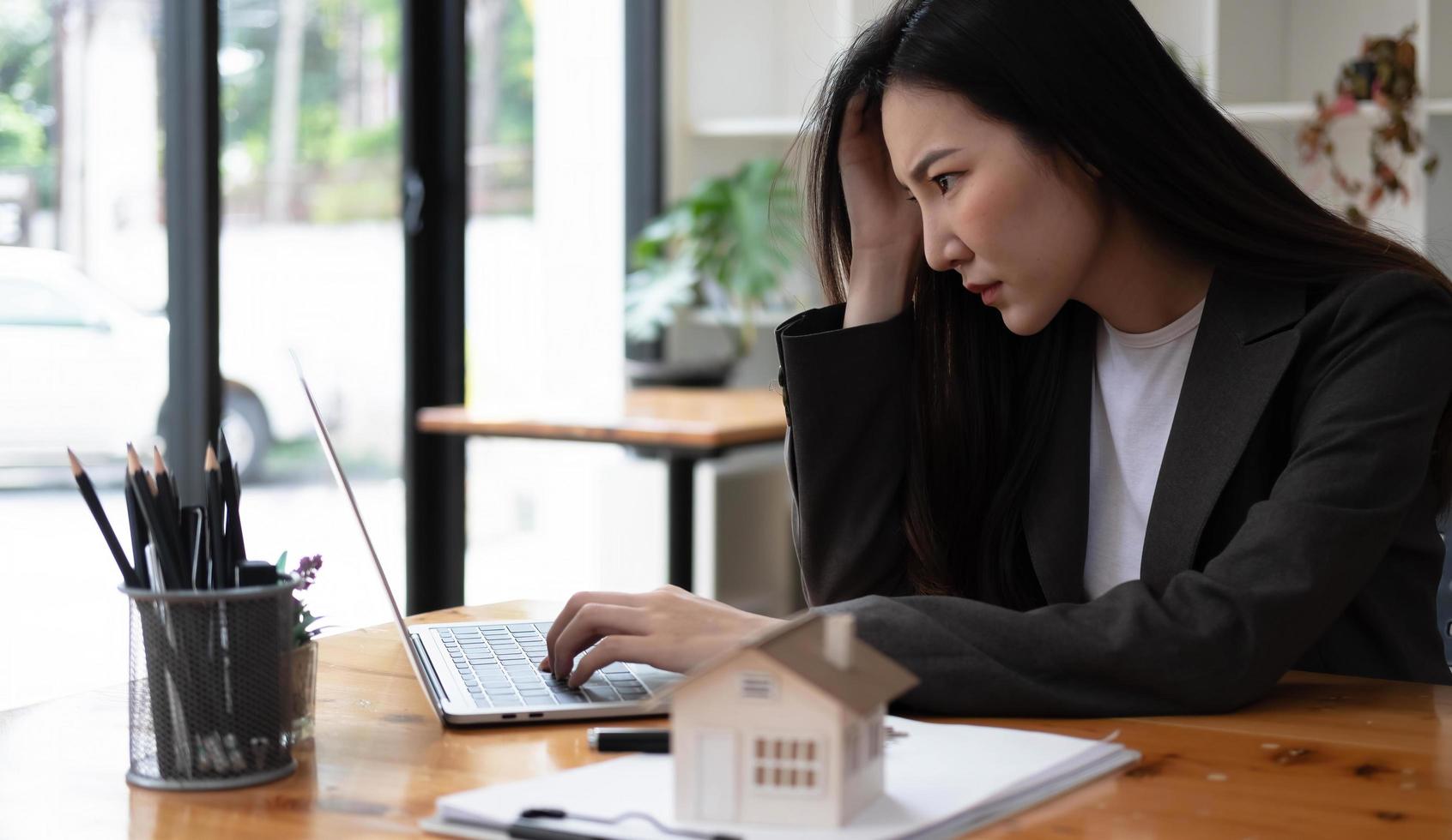 gestresste zakenvrouw die denkt aan te koop onroerend goed haar zakelijk project en strategie op een laptopcomputer op kantoor foto