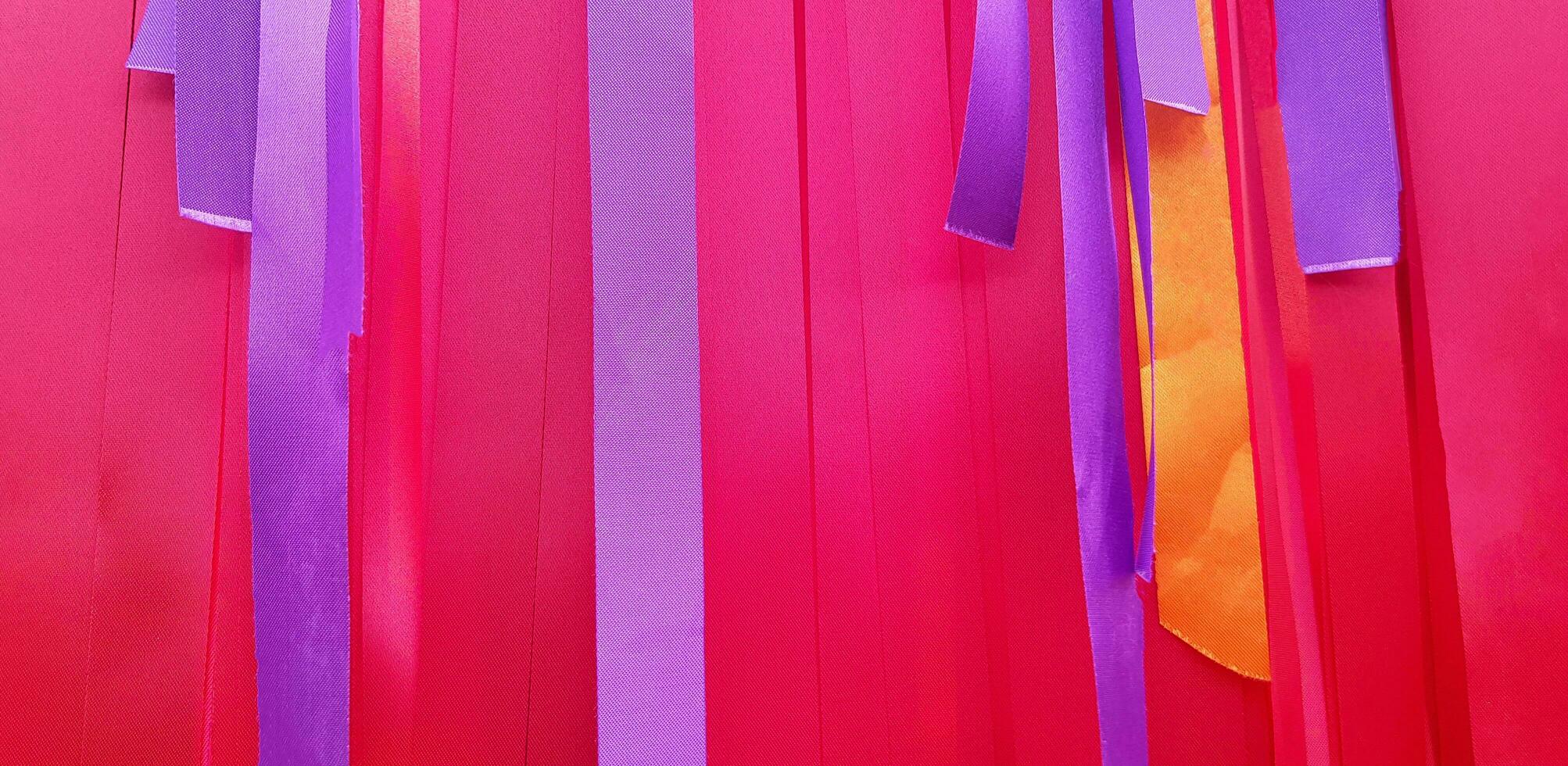 Purper of paars, roze en oranje lint achtergrond of muur. pastel en kleurrijk papier of kleding stof decoratie in partij, festival, bruiloft, nieuw jaar en viering concept. foto