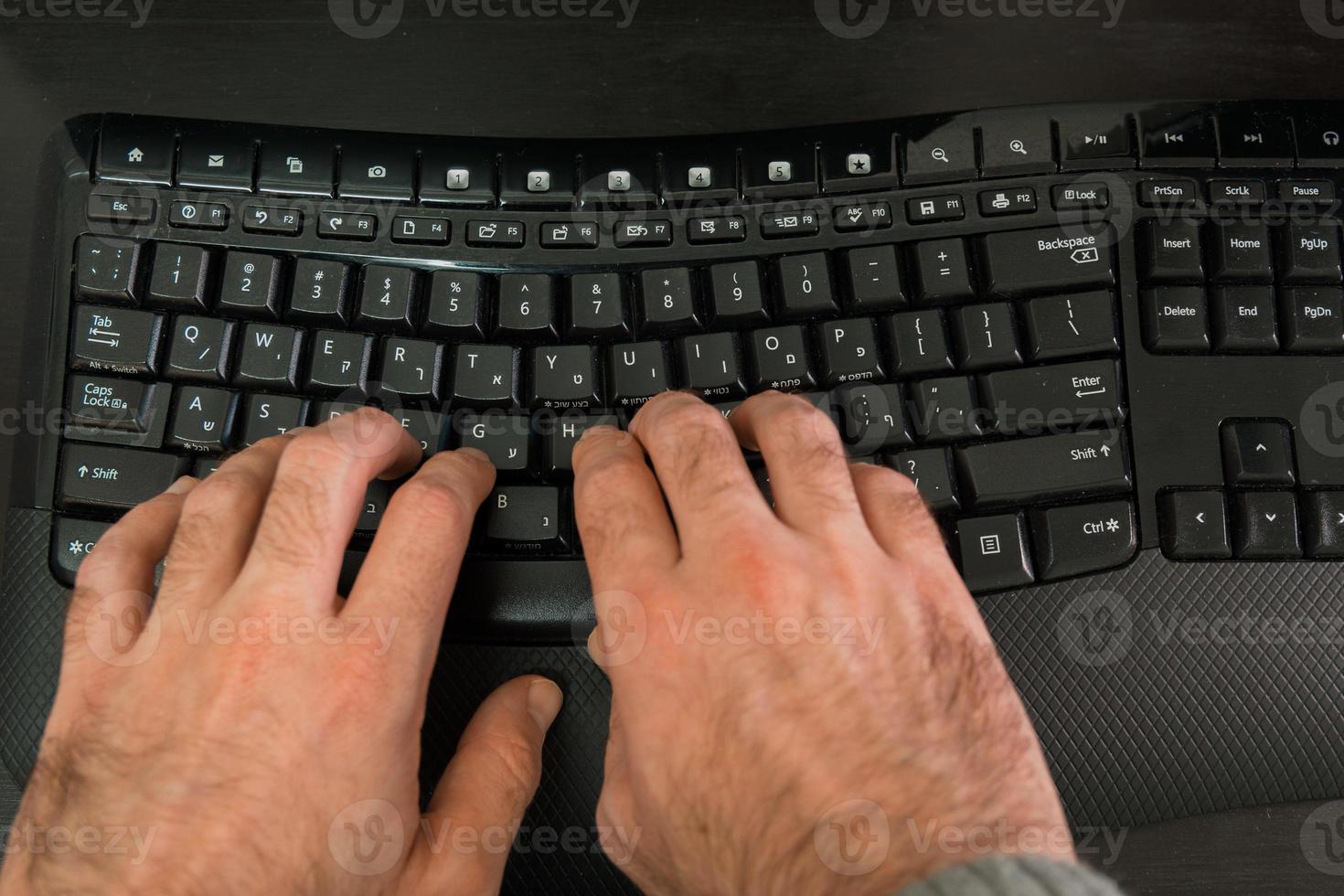 man typt op een toetsenbord met letters in het hebreeuws en engels foto