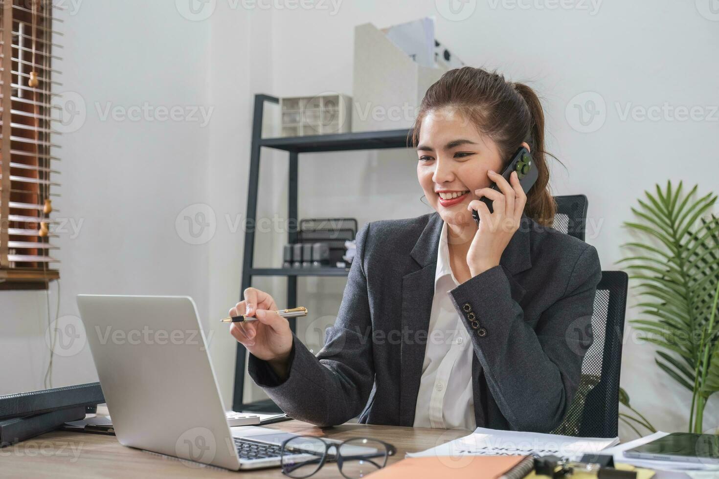 zakenvrouw pratend Aan bedrijf telefoon en gebruik makend van laptop naar Doen financiën, wiskunde Aan houten tafel in kantoor en bedrijf achtergrond, belasting, boekhouding, statistieken en analytisch Onderzoek concepten. foto