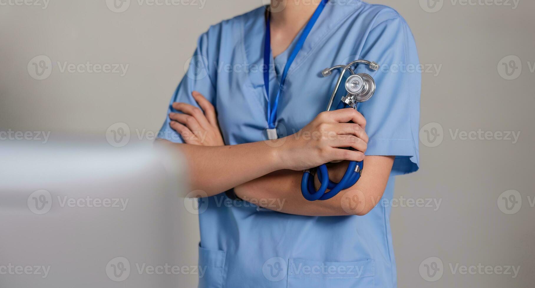 dichtbij omhoog een dokter staand met zijn armen gekruiste Holding een stethoscoop, een dokter van de ziekenhuis. medisch personeel mensen. team van dokter en verpleegster in ziekenhuis. concept van medisch foto