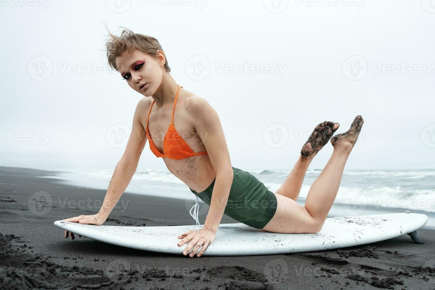 sport- mode model- surfer aan het liegen Aan surfplank, leunend Aan handen, gebogen terug en op zoek Bij camera foto