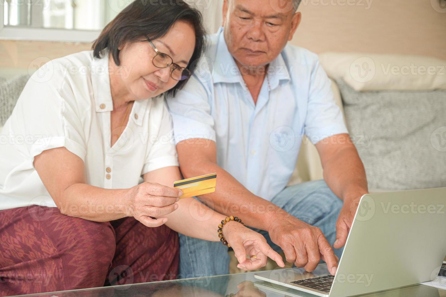 Aziatische vrouwen en mannen zitten op de bank. ze gebruiken laptops en raadplegen online betalingen met creditcard. foto