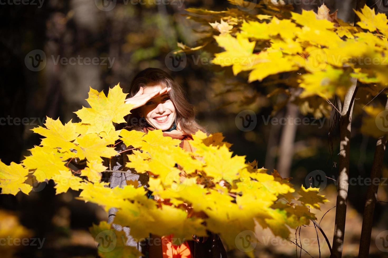 jonge vrouw staat tussen gele herfstbladeren foto