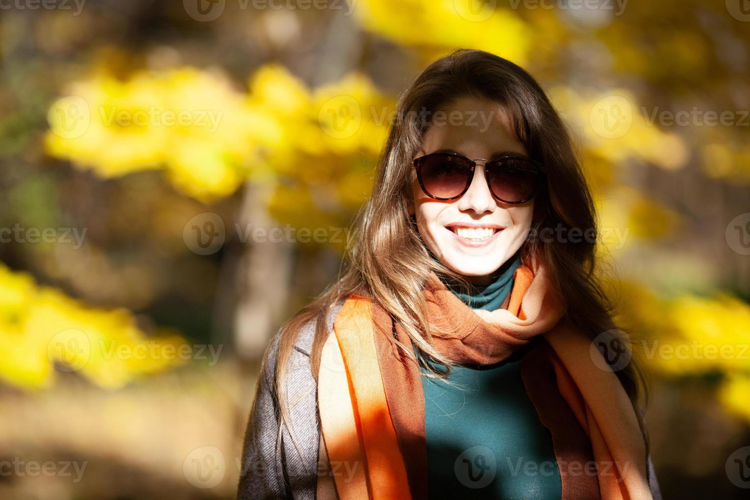 jonge vrouw in zonnebril in de stralen van de herfstzon foto