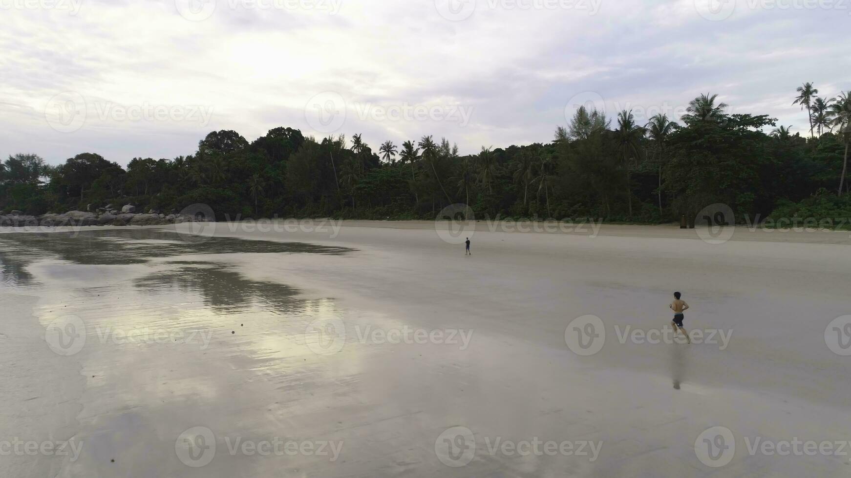 antenne voor Mens jogging Aan een tropisch zanderig strand in de buurt de zee. schot. mooi antenne visie van een loper Mens opleiding Aan de strand. foto