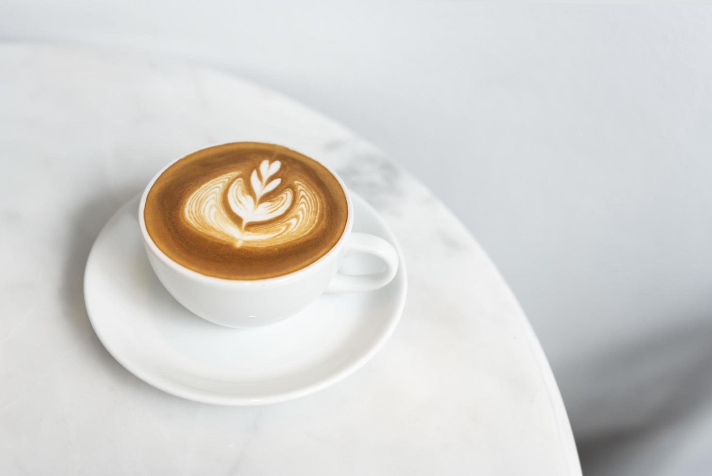 latte of cappuccino met schuimig schuim, koffiekopje bovenaanzicht op tafel in café. foto