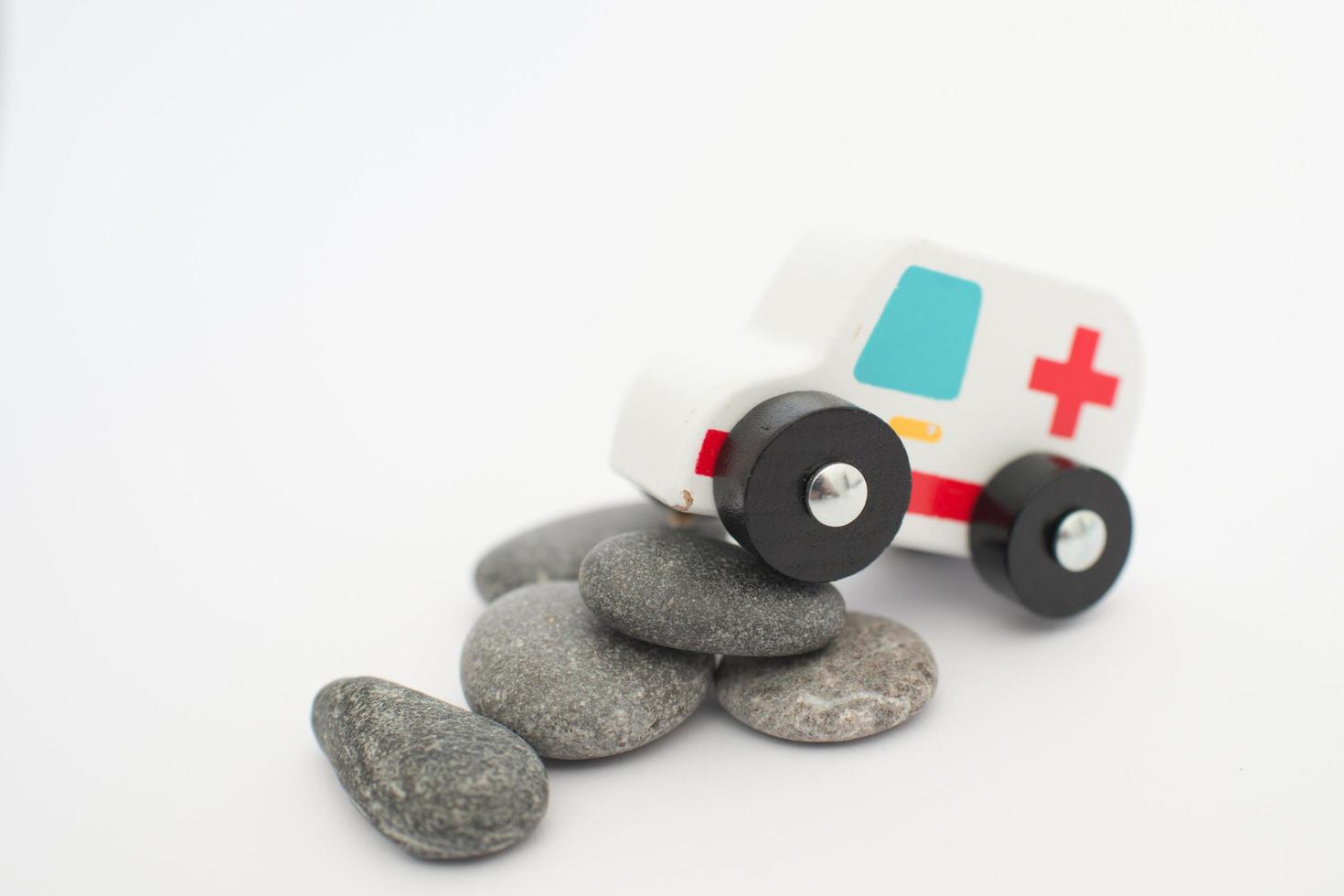 close-up van een ambulance, houten speelgoed, te maken krijgen met stenen op zijn weg. conceptueel voor tegenspoed, problemen, strijd of crisis foto