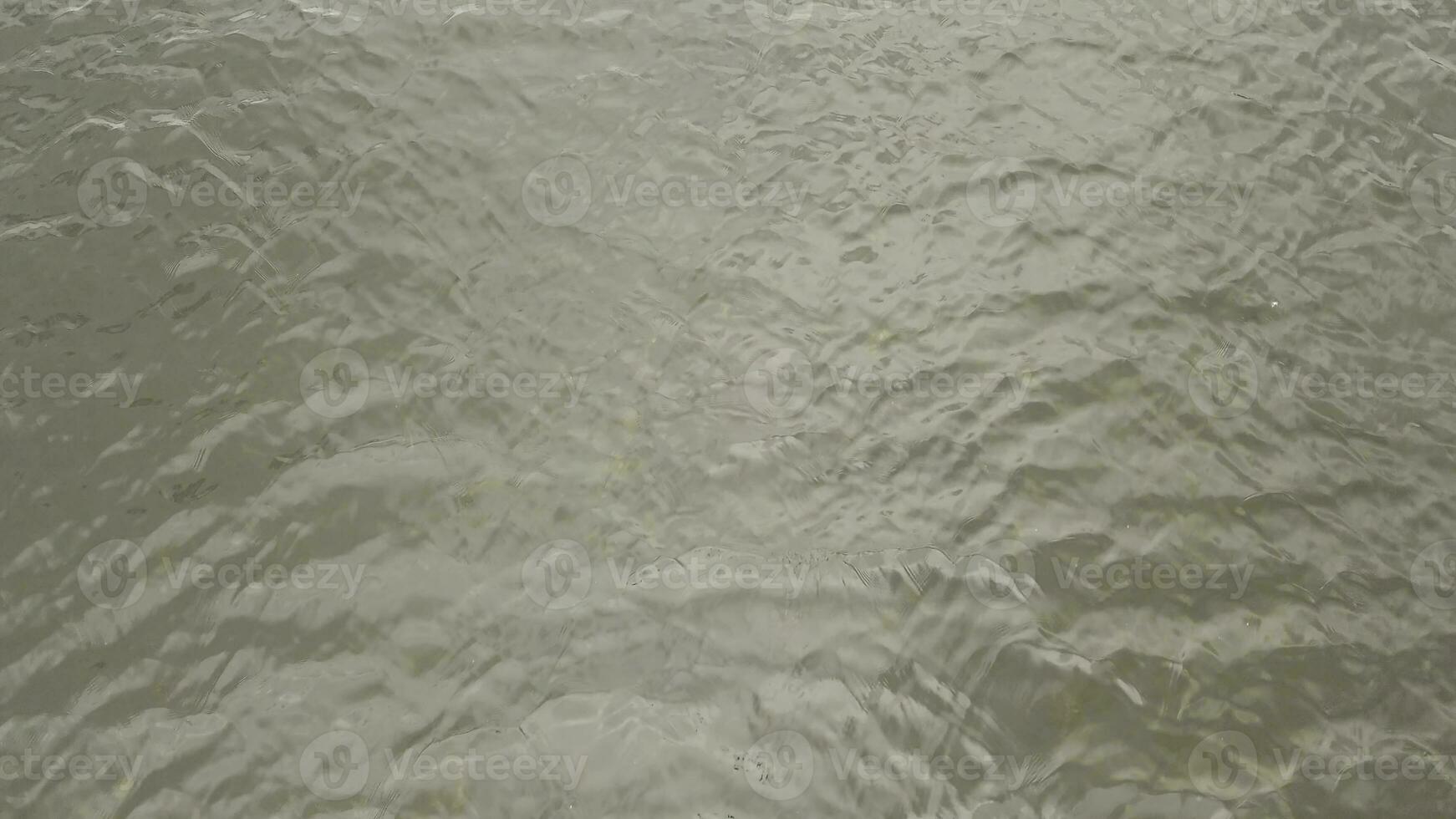 water oppervlakte met rimpelingen en zonnestralen reflectie. voorraad filmmateriaal. zomer rivier- achtergrond met klein golven van vuil water. foto