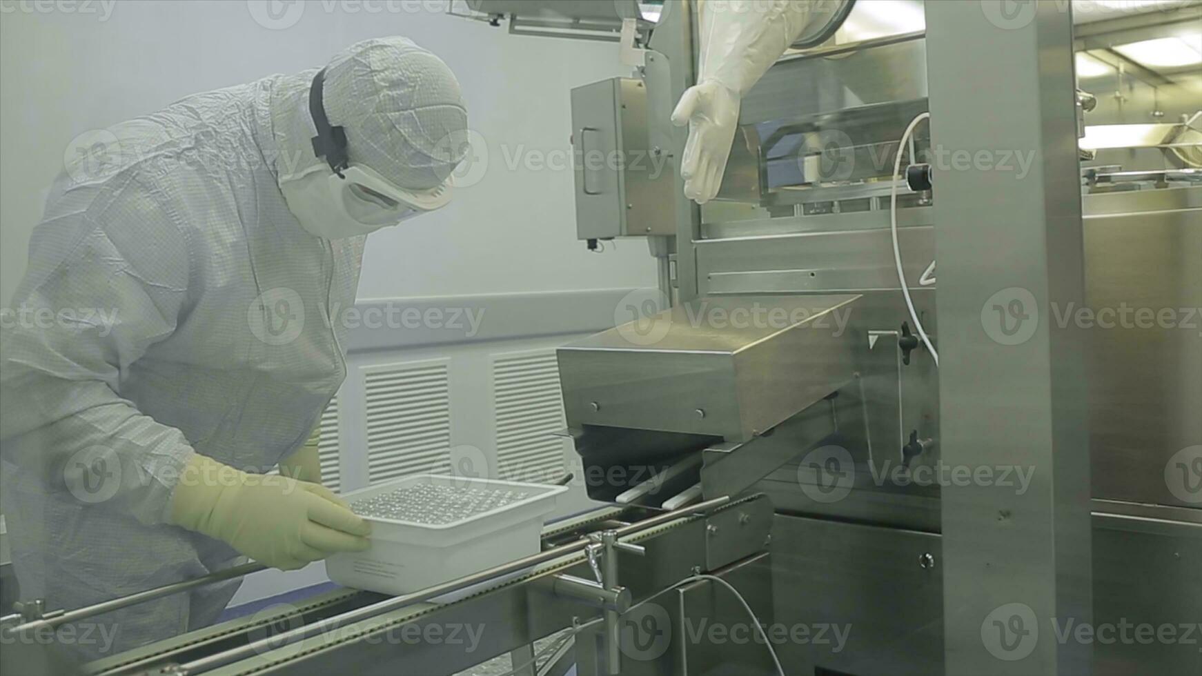 farmaceutisch industrie. mannetje fabriek arbeider inspecteren kwaliteit van pillen verpakking in farmaceutisch fabriek. automatisch plakband naar creëren verpakking en vulling van geneesmiddelen. controle in de fabriek van foto