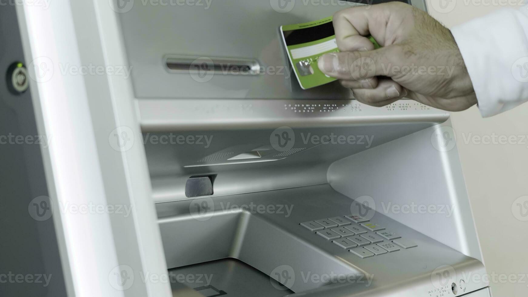 mannetje hand- Vastmaken kaart naar de Geldautomaat bank machine voor het uitvoeren van financieel transacties. hdr. dichtbij omhoog van Mens binnengaan bank kaart pin code. foto