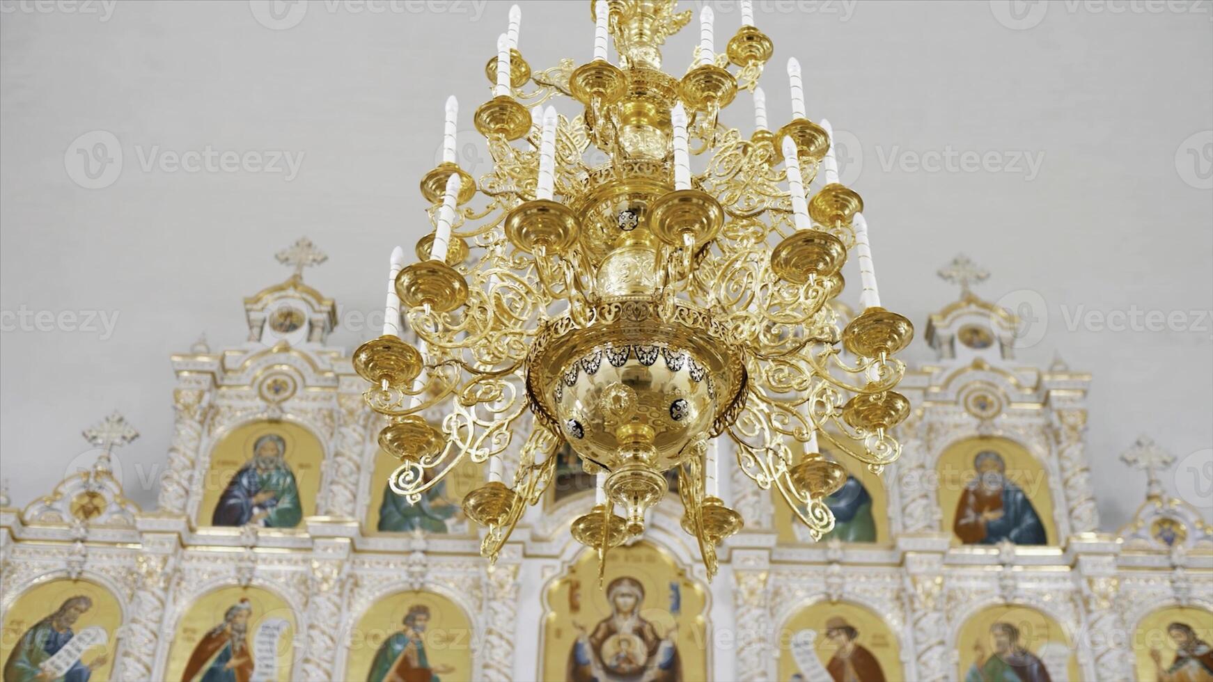 christen orthodox kerk interieur in wit en gouden kleuren. video. kroonluchter met kunstmatig kaarsen in de tempel met iconostase. foto