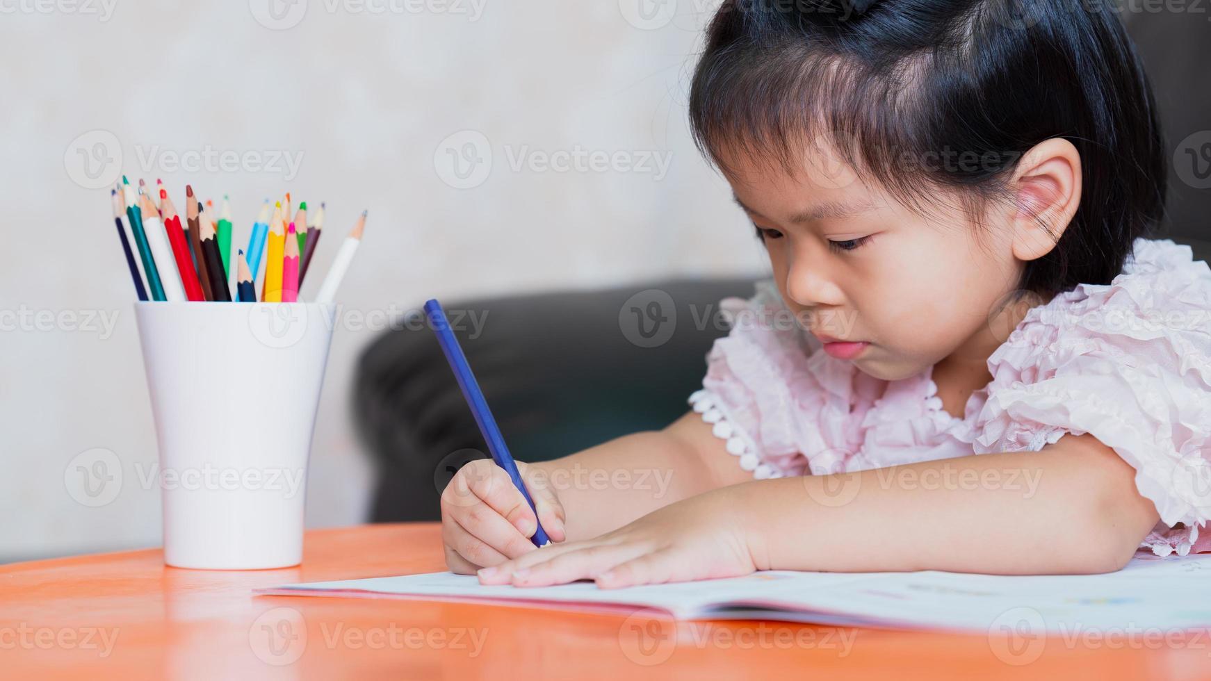 klein kind meisje tekening thuis creativiteit ontwikkeling, handen detail van een jonge kinderen kleur tekening met veelkleurige potloden. foto
