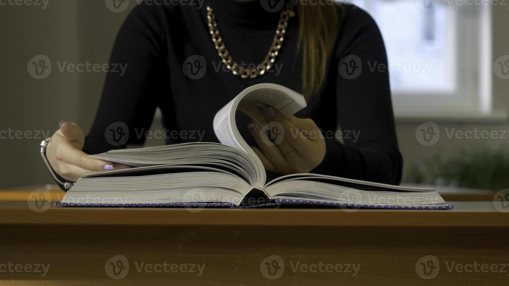 vrouwen handen bladeren door een boek. vrouw zittend Bij de tafel bladeren door de boek foto