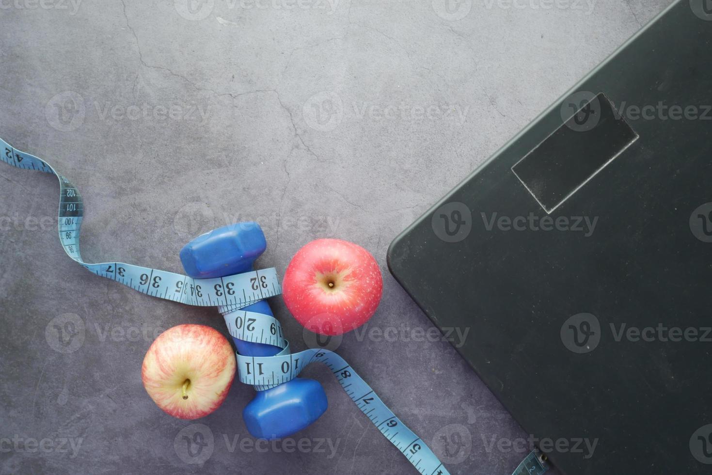 fitnessconcept met halter, appel en weegschaal op zwart foto
