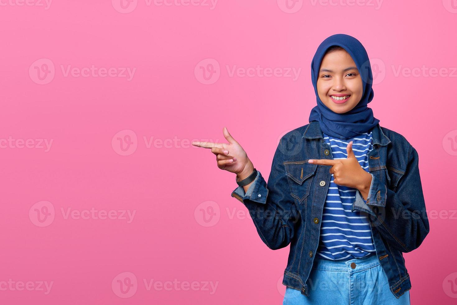 portret van een glimlachende jonge aziatische vrouw die met de vinger naar de ruimte wijst? foto