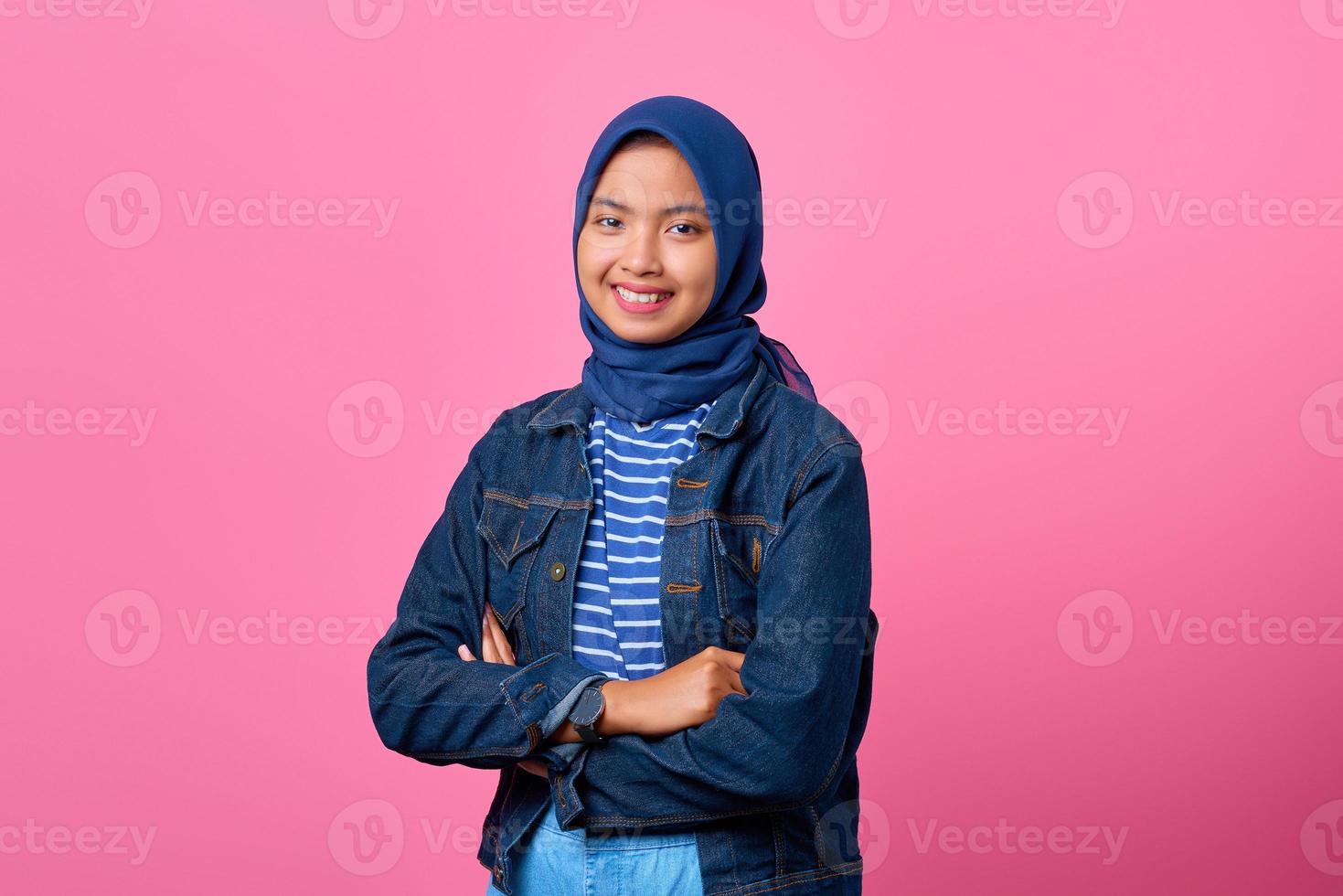 portret van glimlachende jonge aziatische vrouw die camera met gekruiste armen bekijkt foto