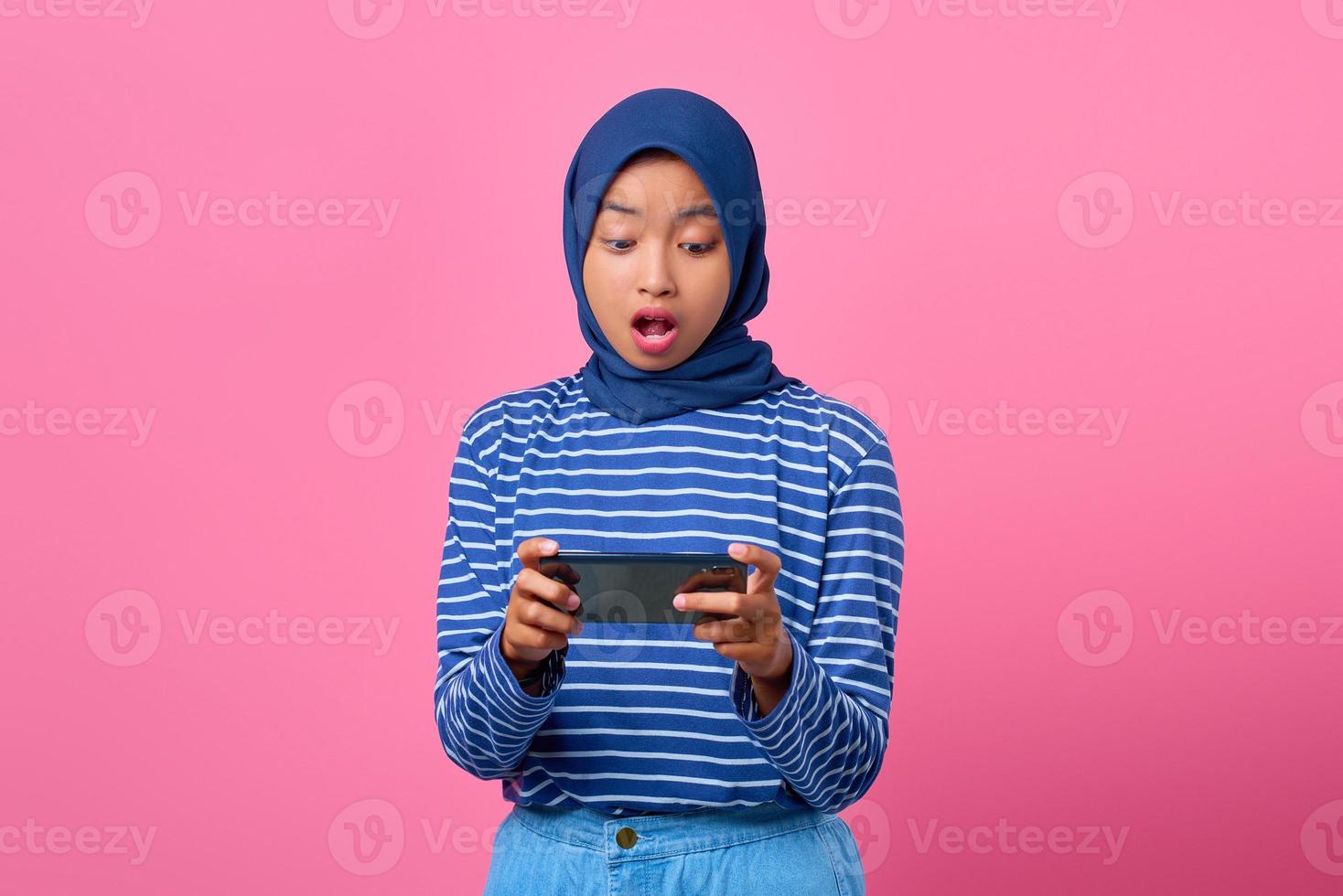 portret van geschokte jonge aziatische vrouw die videogame speelt op mobiele telefoon foto