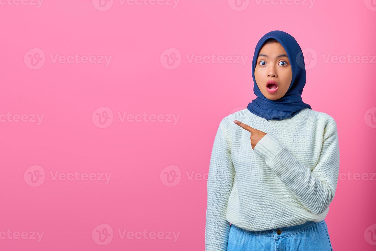 portret van een geschokte jonge aziatische vrouw die met de vinger naar de ruimte wijst? foto