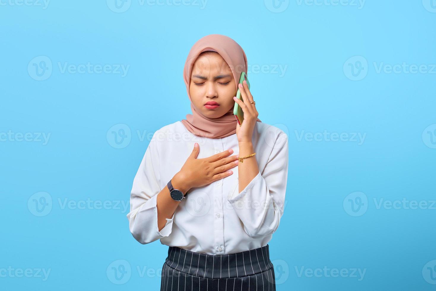 portret van verdriet jonge Aziatische vrouw praten op mobiele telefoon met een andere hand op de borst foto