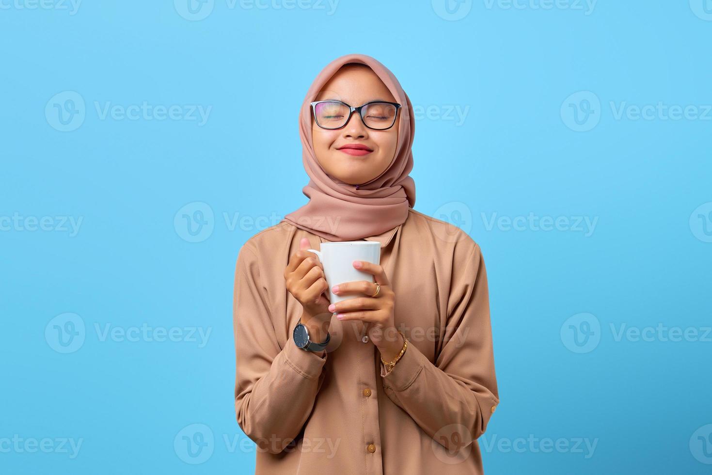 portret van geluk jonge Aziatische vrouw hand houden mok over blauwe achtergrond foto