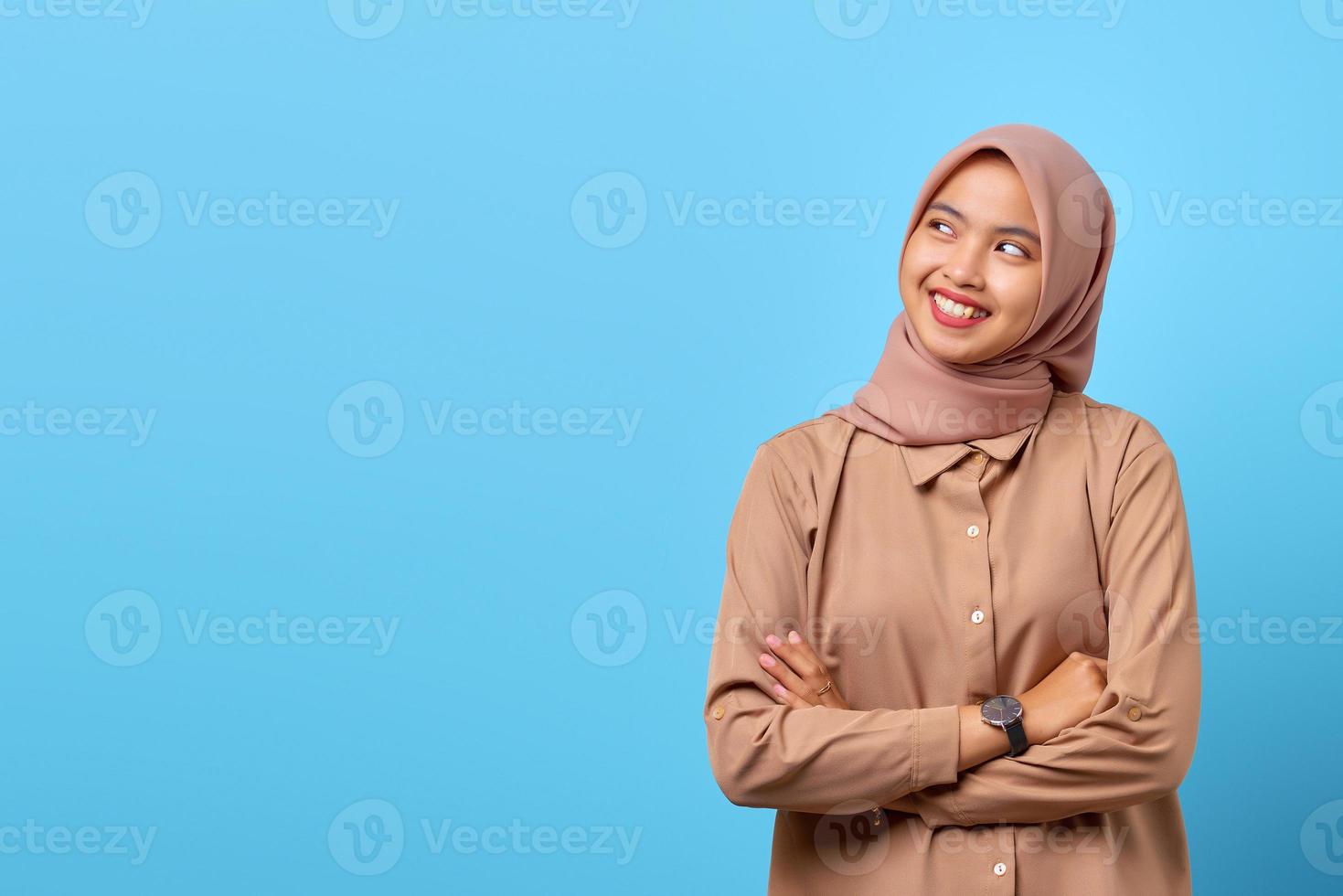 portret van glimlachende jonge aziatische vrouw die naar de kant kijkt met gekruiste armen foto