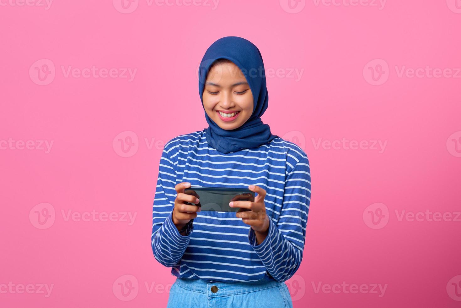 portret van gelukkige jonge aziatische vrouw die videogame speelt op mobiele telefoon foto