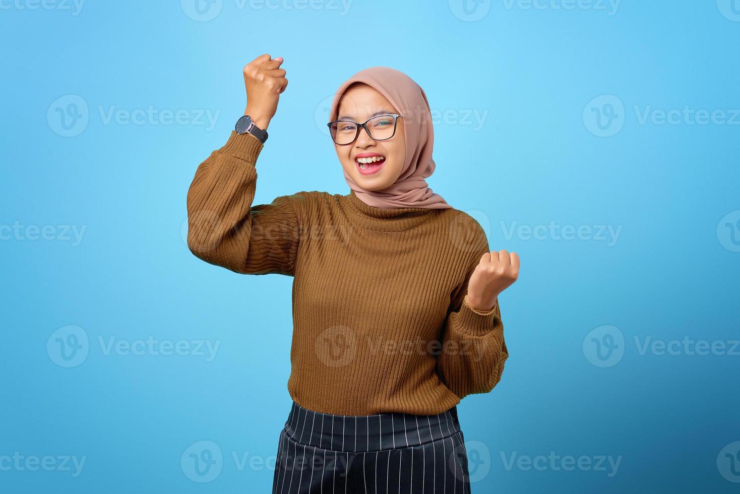 portret van vrolijke mooie aziatische vrouw die zich verheugt over het vieren van geluk op blauwe achtergrond foto